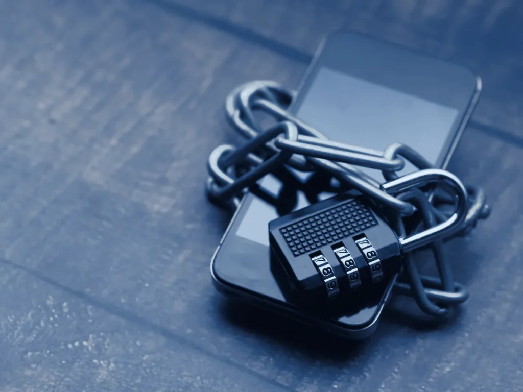 Téléphone intelligent entouré d'une chaîne et verrouillé par un cadenas, illustrant la cybersécurité